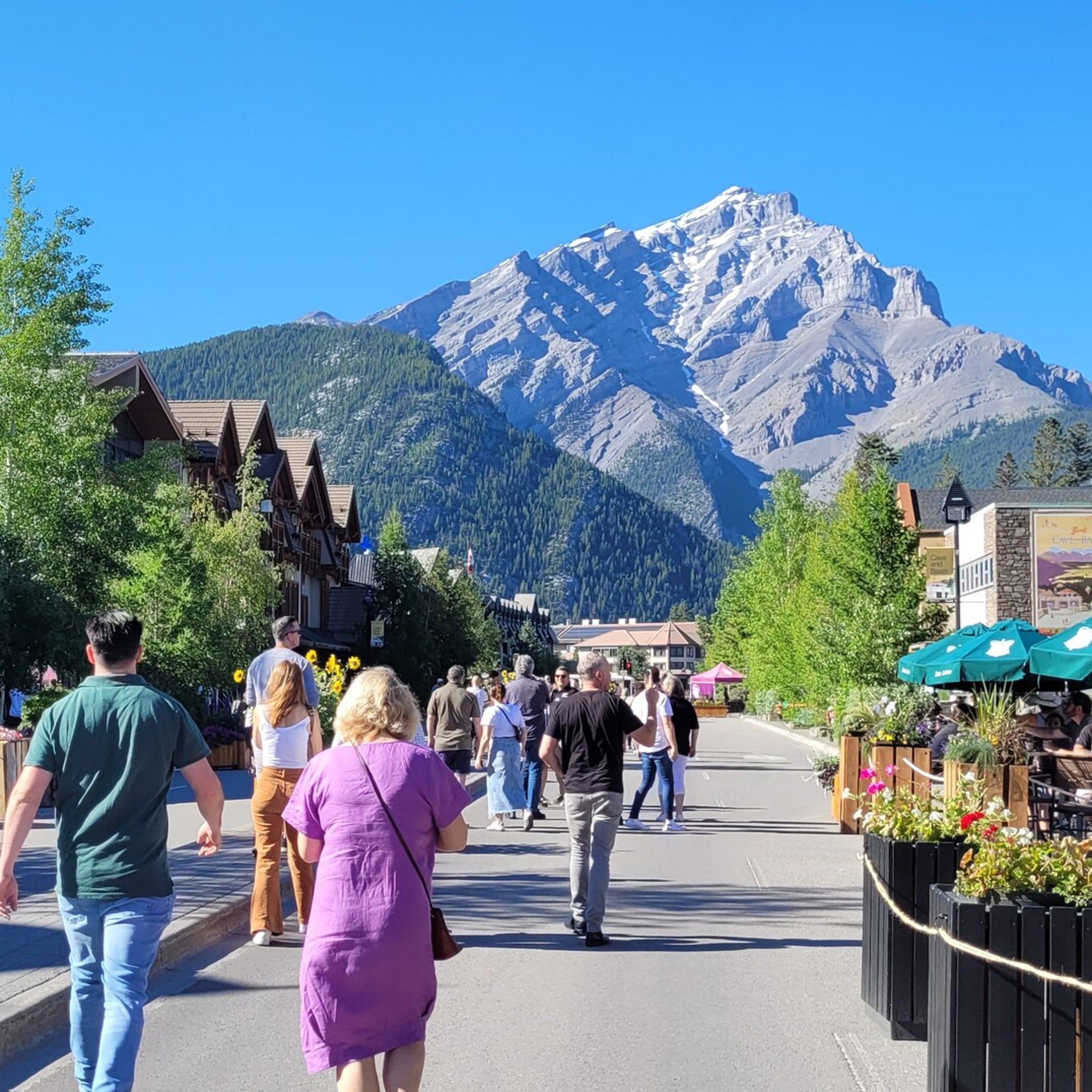 Group of people walking towards a mountain down the main street in Banff Canada