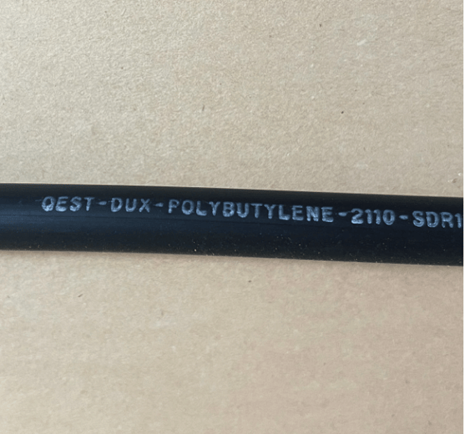 black pipe showing qest-dux-polybutylene in white text