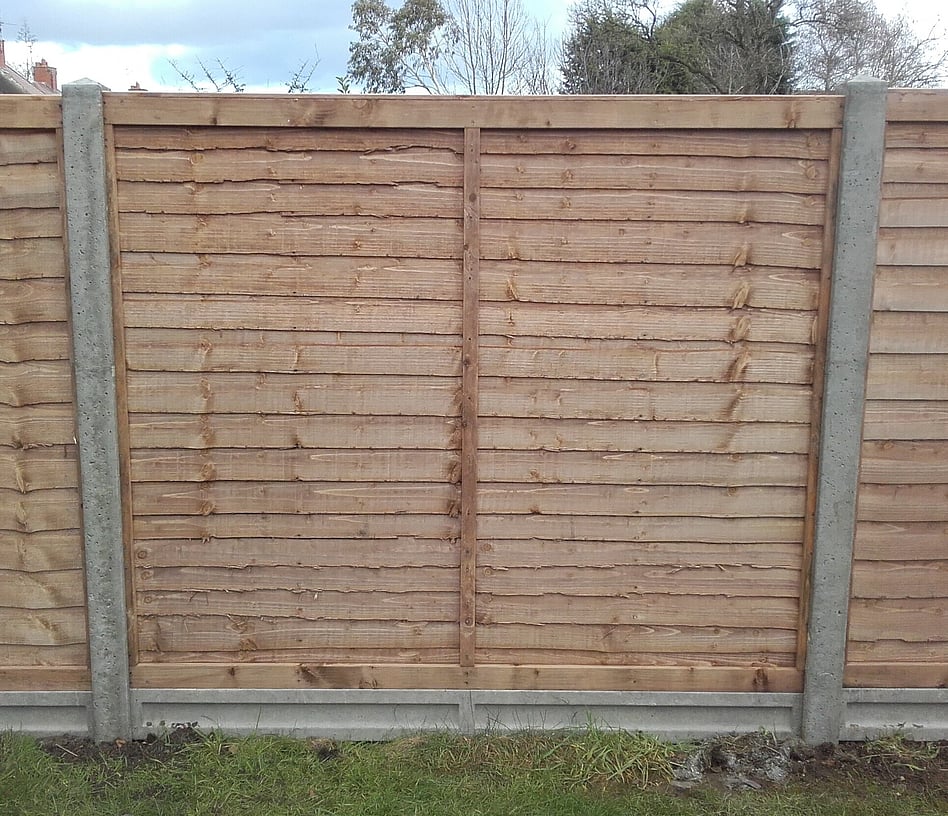 Image shows one 5' overlap fence panel sitting on a 6" concrete gravelboard and fitted to slotted concrete posts at both ends.