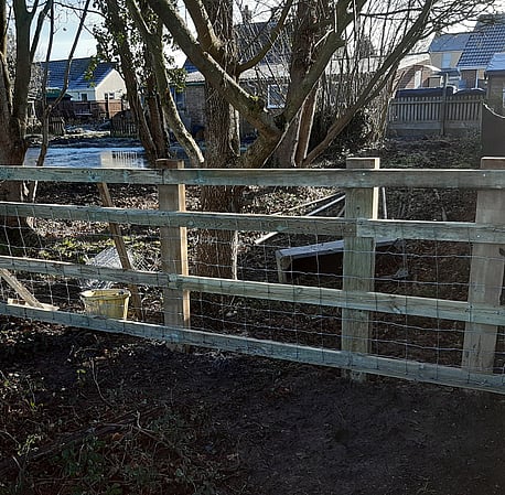 Post and rail fencing with stock netting attacjhed.