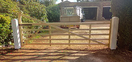 a 3.6mt wide Timber field gate hanging from curved top timber posts.