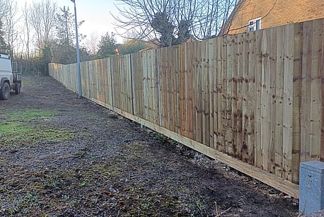 A run of timber closeboard fencing installed using recessed concrete posts and cant rails.