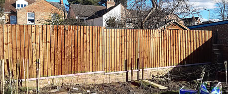 Image shows completed closeboard fence from the front (neighbours) view. From this side you cannot see the frame work of the fence (posts and rails) just the feather edge boards. The fence components are all pre treated with Brown Tanatone wood treatment.
