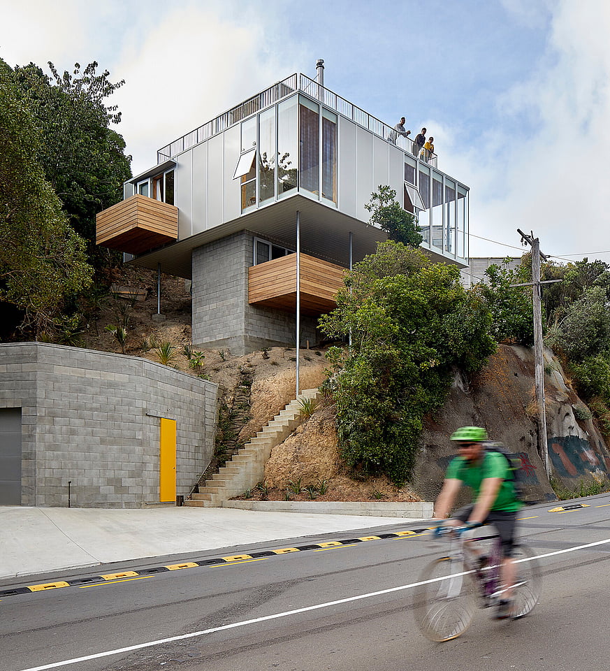 Architectural home with people looking down from the rooftop deck.