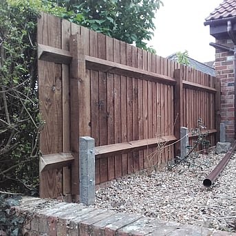 Image shows a short section (about 12') of low closeboard fencing that had concrete repair spurs fitted from new. This will prevent the posts rotting out. 