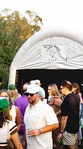 Man in crowd at an outdoor Daddy Shack Austin golf simulator event