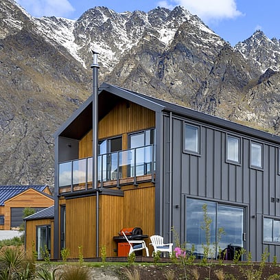 Looking up at the end of the house with the balcony and the Remarkable Mountain range in the background.