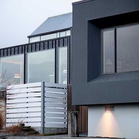 The exterior of the home with feature lighting and large windows looking out.