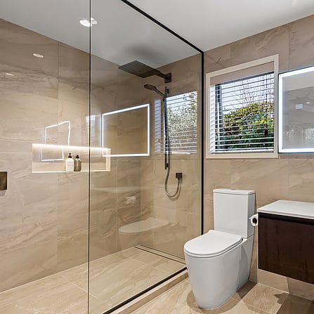 A beautiful warm neutral toned tiled bathroom with large glass shower.