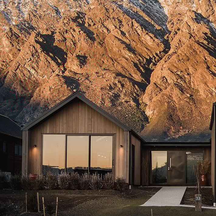 The sun setting over the home exterior with the Remarkable mountain range in the background.
