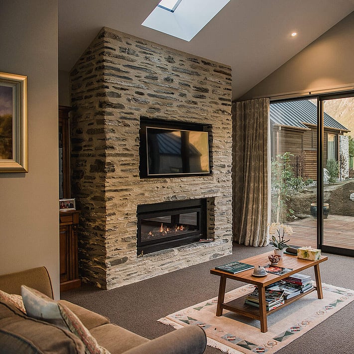 A stacked stone inbuilt fireplace feature in the lounge with coffee table and sofas.