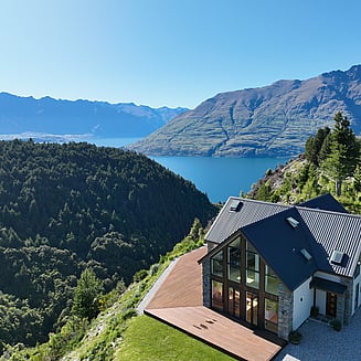 A cozy bedroom with a large bed, light walls, floral duvet and rattan headboard.