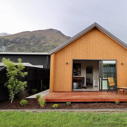 The front of the house extension clad in Luna Wood, with a sliding door opening onto timber decking.