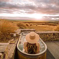 Guest soaking in an outdoor bath at sunset in the Mackenzie Basin