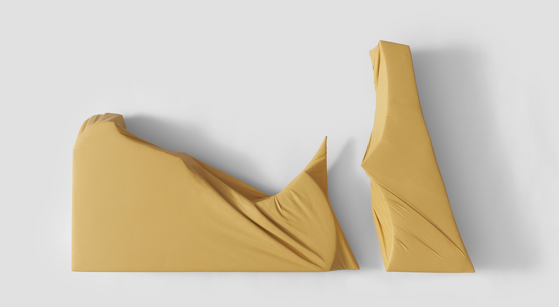 Limestone coloured wrapped wall sculpture with curves and straight lines, folds and tensions on the painted canvas wrapping. the sculpture is in two parts with a variable distance between the two sections casting sculptural shadows