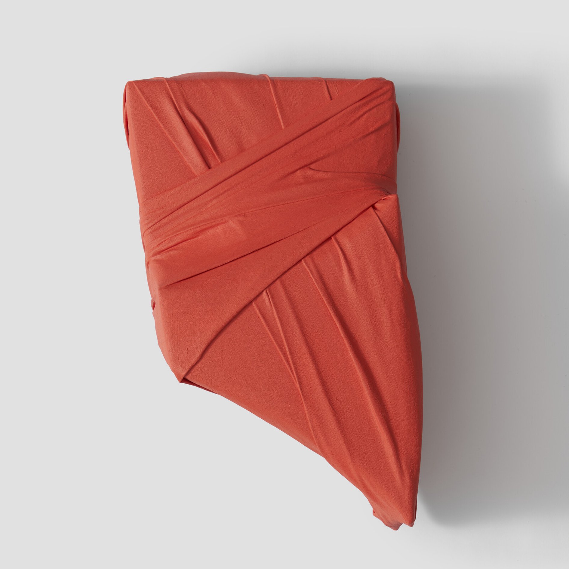 orange small wrapped wall sculpture with folds and curves.