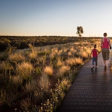 A parent holding a childs hand while walking down a road.