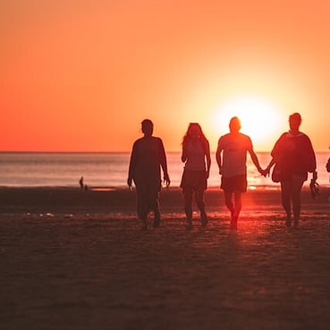 A family walking down a beach together at sunset.