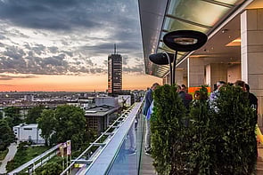 Rooftop bar patrons are kept warm by beautiful radiant heaters.