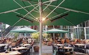 Heaters under patio umbrellas, ready to keep guests warm during the colder months