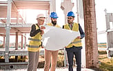 People standing within a construction site reviewing a site drawing