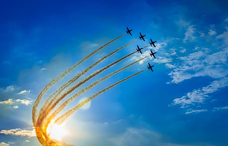 Group of aeroplanes flying together in sky with jet mist