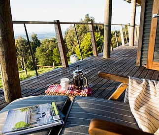deck chair with coffee and magazines set up on the expansive deck looking out over countryside below