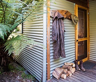 logs for fire stacked outside with rustic boots and coat