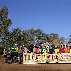 The group of cyclists holding 'Bike'n Wheels' sign