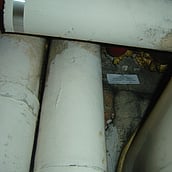 Asbestos insulation debris to a boiler room ceiling