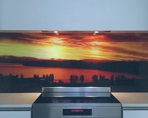 Image of a glass printed splashback of a landscape situated behind an electric cooktop.