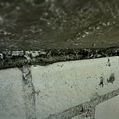Asbestos spray coating within ceiling gap