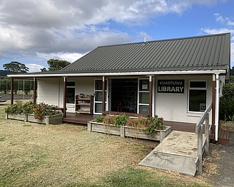 The exterior of the Kūaotunu library showing the ramp up to the deck and the double doors wide open.