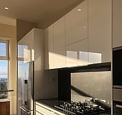 Custom kitchen design featuring two-pac painted panels, honed black and polished Blue Pearl granite.
