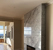 Gas fireplace with polished Carrara marble and honed black hearth.