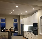 Custom kitchen design featuring two-pac painted panels, honed black and polished Blue Pearl granite, and Tassie Oak butcher block to match the flooring.