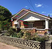 Photo shows the previous 1925 bungalow condition, including non-original white paint and screen block wall