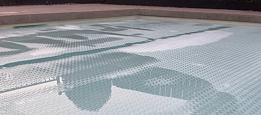 Showing top of pool with pool cover on, showing edge of swimming pool in background