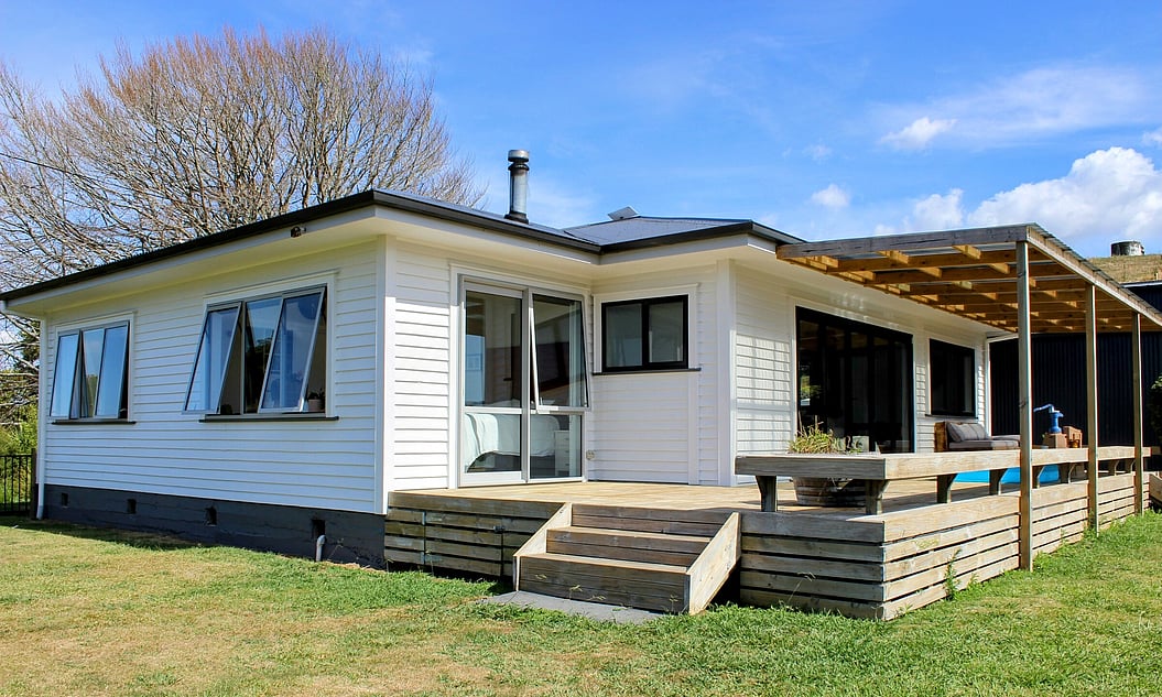 Image of the recently renovated weatherboard home painted white with dark roofing and new decking. By Coull Builders, Otorohanga.