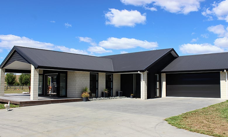 Image of large stone coloured brick home with dark roofing, doors and joinery. New home by Coull Builders, Otorohanga.