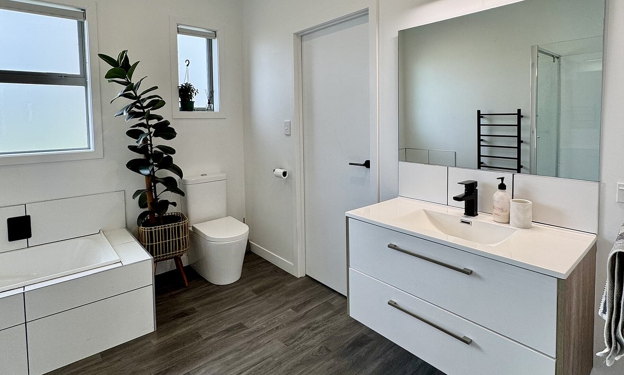 Fresh new white tiled bath, toiler and black tiled bathroom by Coull Builders, Otorohanga.