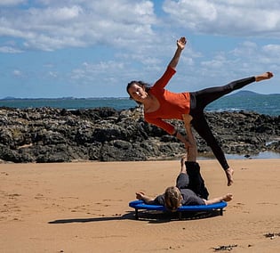 Couple doing acrobatics on a XenPod at the beach