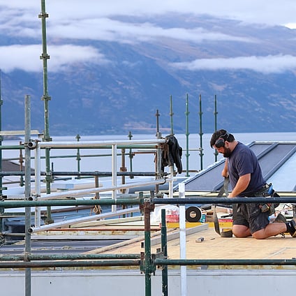 Builders working on site at a home renovation with lake Wakatipu, Queenstown in the background.