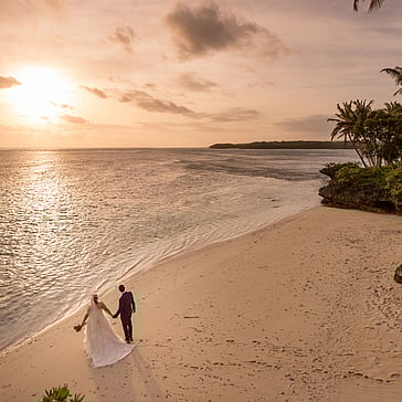 Couple walking along a secluded beach as part of a luxury destination wedding or honeymoon experience