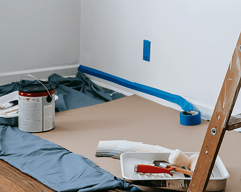 Interior painting equipment - paint, brushes and rollers, a ladder, masking tape and drop cloths.   Photo by Blue Bird: https://www.pexels.com/photo/brown-wooden-stepladder-in-a-room-7217924/