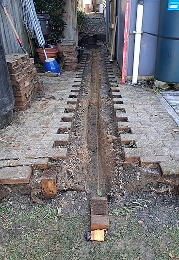 Pavers removed, channel in dirt and string line.