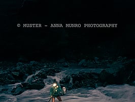 Shepherd female crossing cold river with headtorch. Merino muster with dog. Autumn Muster.  Lake Heron Station, Canterbury High Country, New Zealand