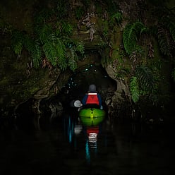 AAmazing vibrant nature as kayaker enters glow worm cave