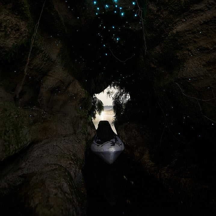 Kayak sitting inside a glow worm cave looking towards the lake as dusk falls