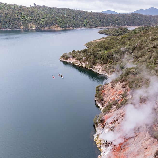 Kayaks on Lake Rotomahana with colour landscapes